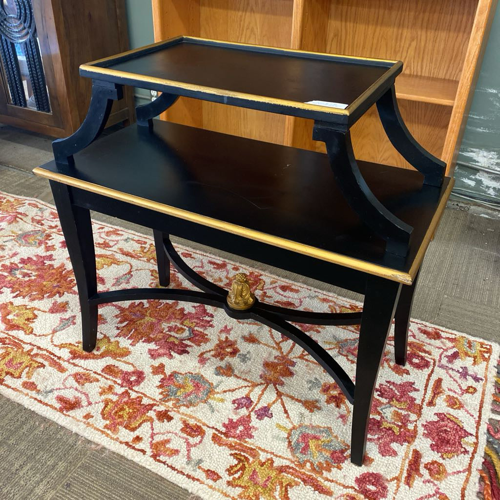 Black wooden side table with gold accents on a patterned rug