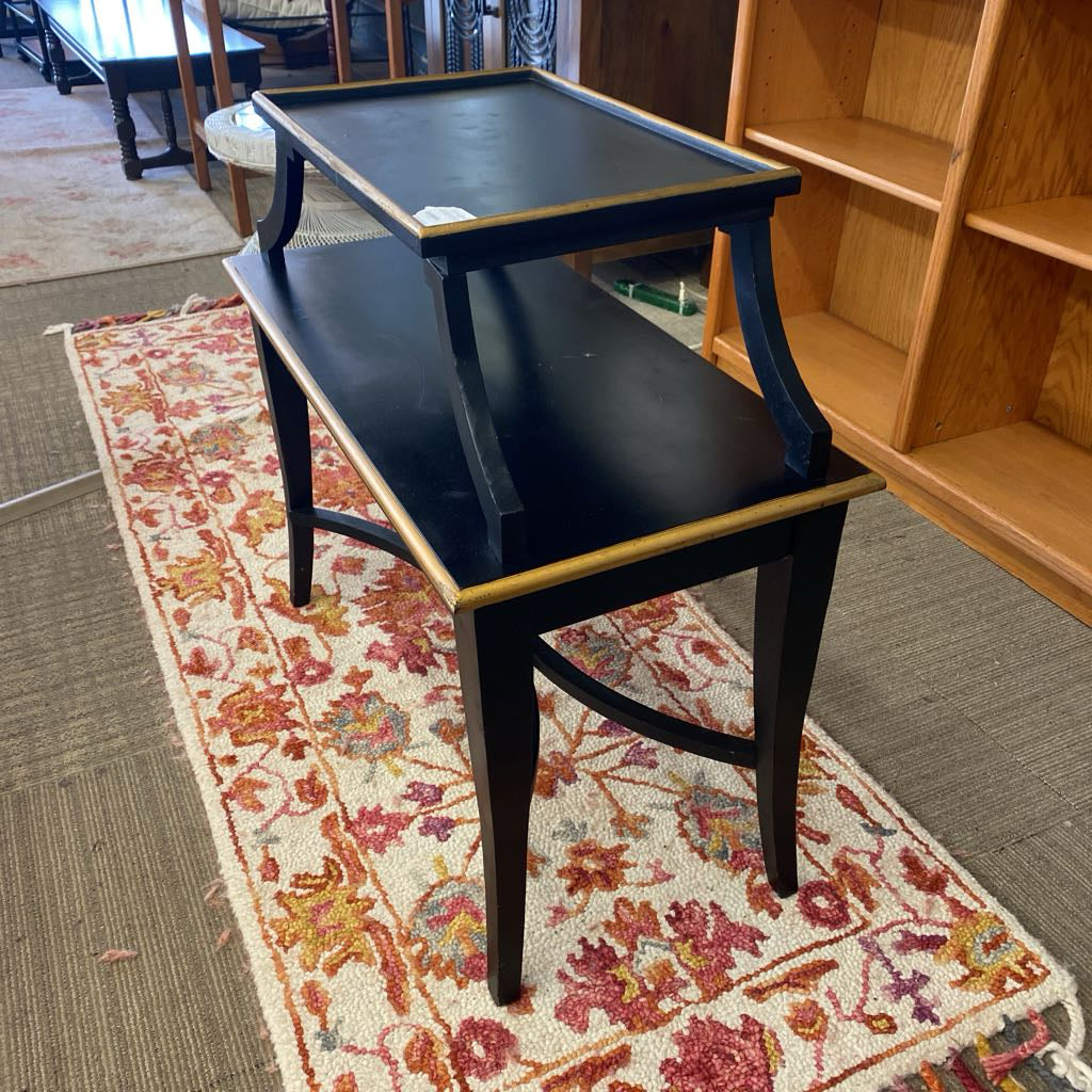 Black bench on a floral rug with wooden shelves in the background