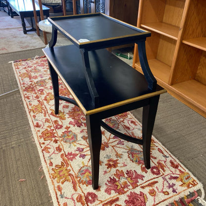 Black bench on a floral rug with wooden shelves in the background
