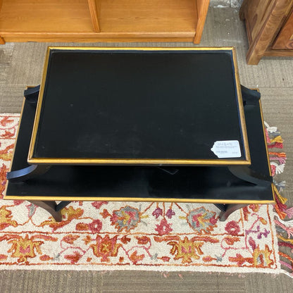 Black coffee table with gold trim on a patterned rug
