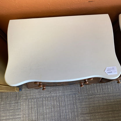 Beige ottoman with wooden legs on a carpeted floor