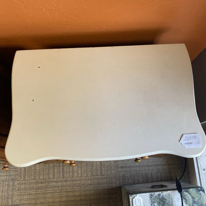 Beige desk with a label on a carpeted floor against an orange wall