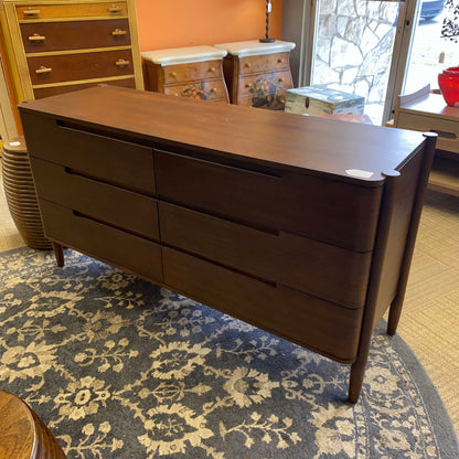 Dark wood dresser on a patterned rug with a room in the background