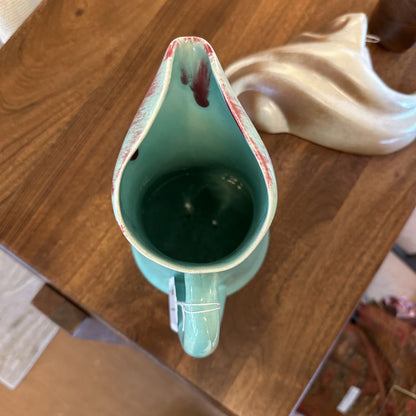Teal pitcher on a wooden surface with a blurred background