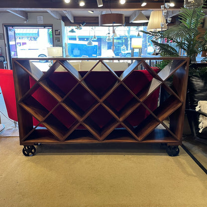 Wooden wine rack on wheels in a room with red sofa and plants