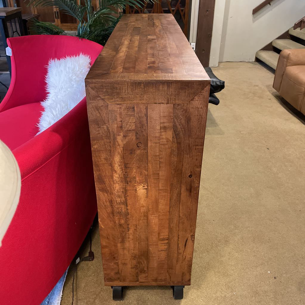 Wooden console table in a room with a red chair and staircase.