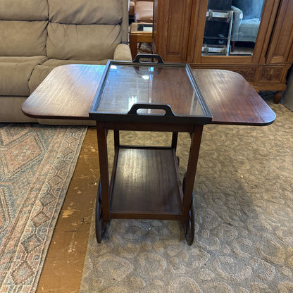 Wooden serving cart with glass top in a living room setting