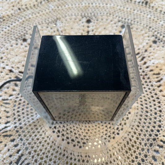 Black square object with reflective surface on a textured beige surface