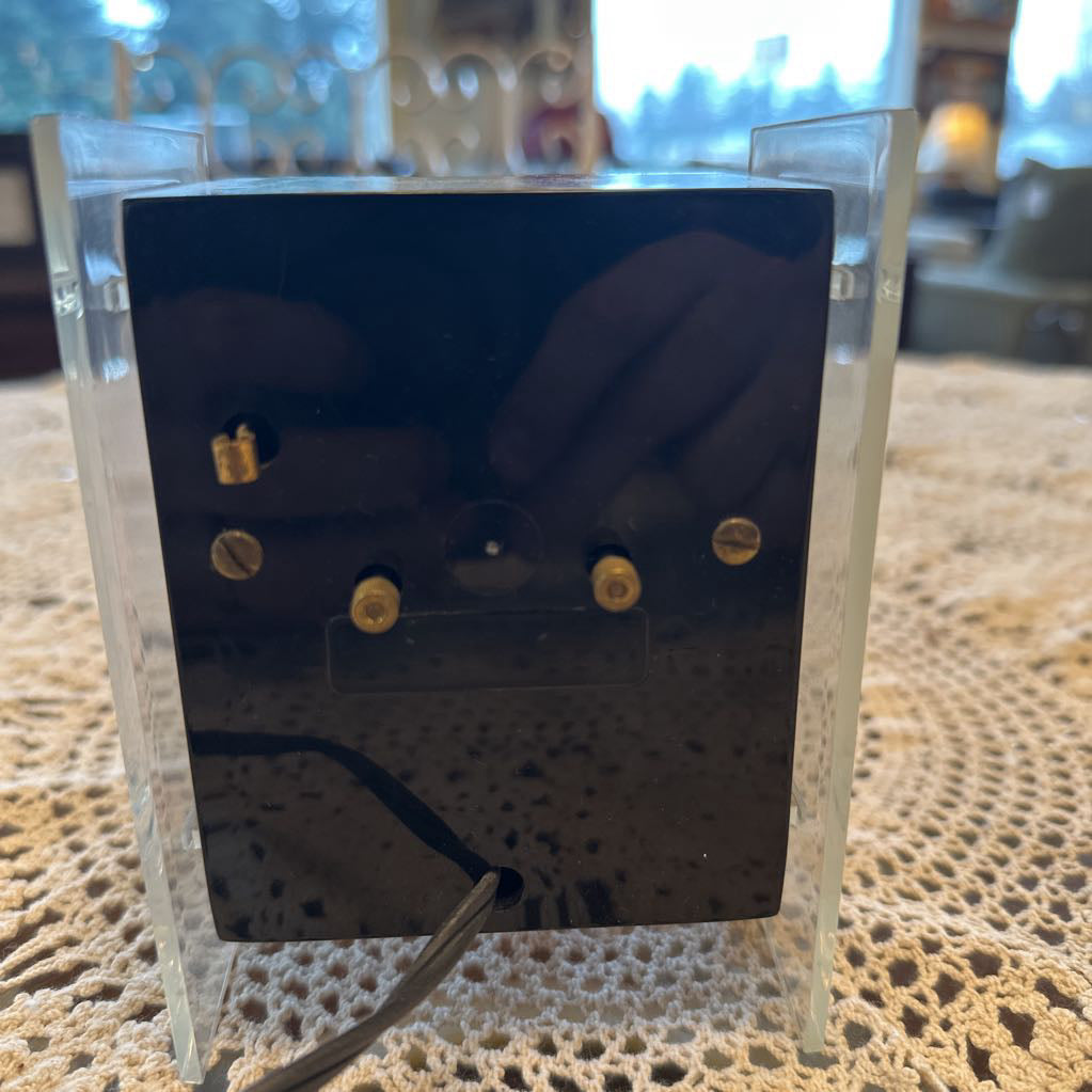 Gold earrings in a clear display case on a textured surface
