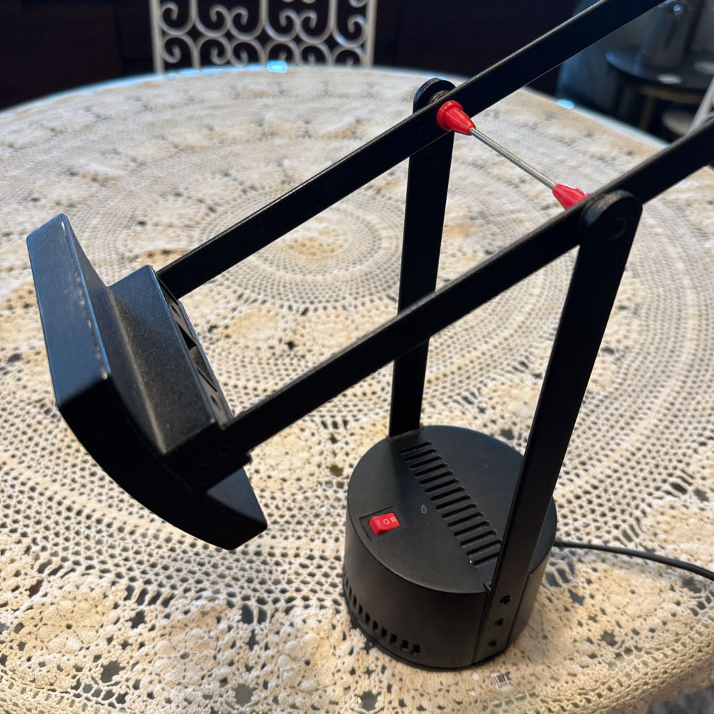 Black metal stand with red accents on a textured surface