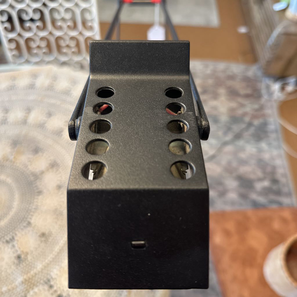 Black metal bracket with multiple holes on a textured surface