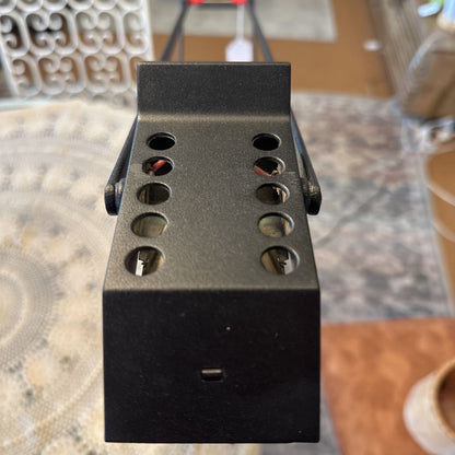 Black metal bracket with multiple holes on a textured surface