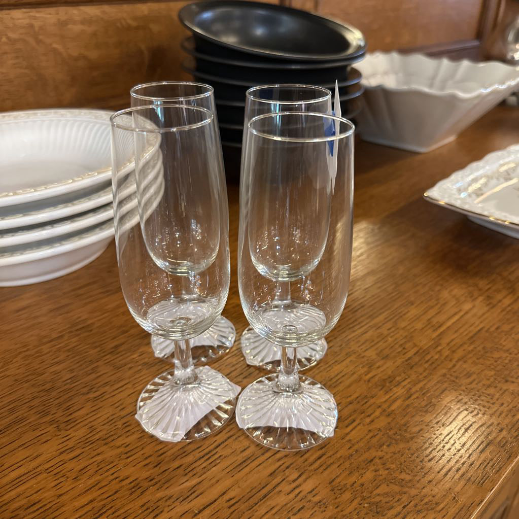 Clear glass goblets on a wooden table with other dishes in the background