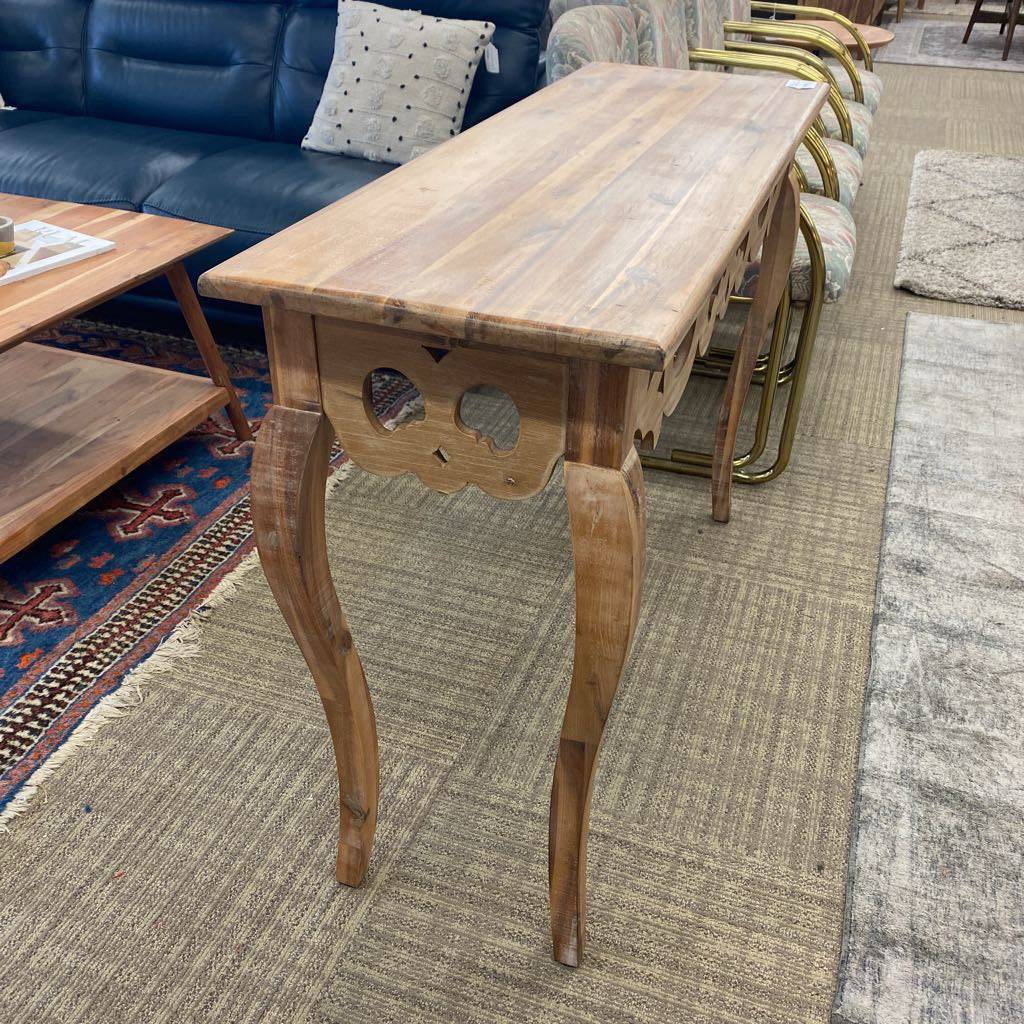 Wooden side table in a living room setting with a sofa and chairs.