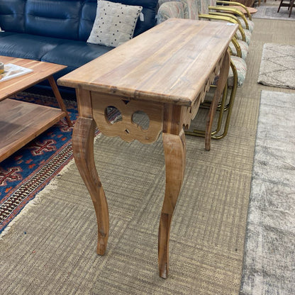 Wooden side table in a living room setting with a sofa and chairs.