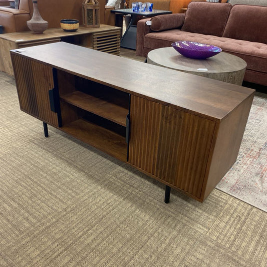 Wooden entertainment console in a living room setting with a sofa and coffee table.