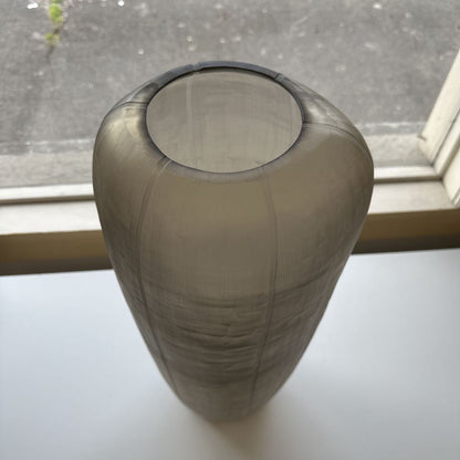 Smoky gray vase on a white surface with a window in the background