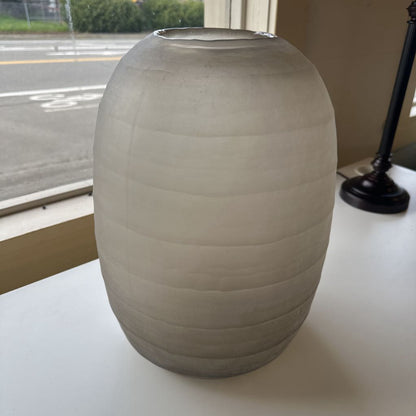 Beige ceramic vase on a white surface with a blurred background