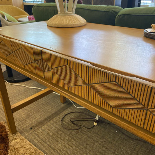 Wooden console table with wicker design in a room setting