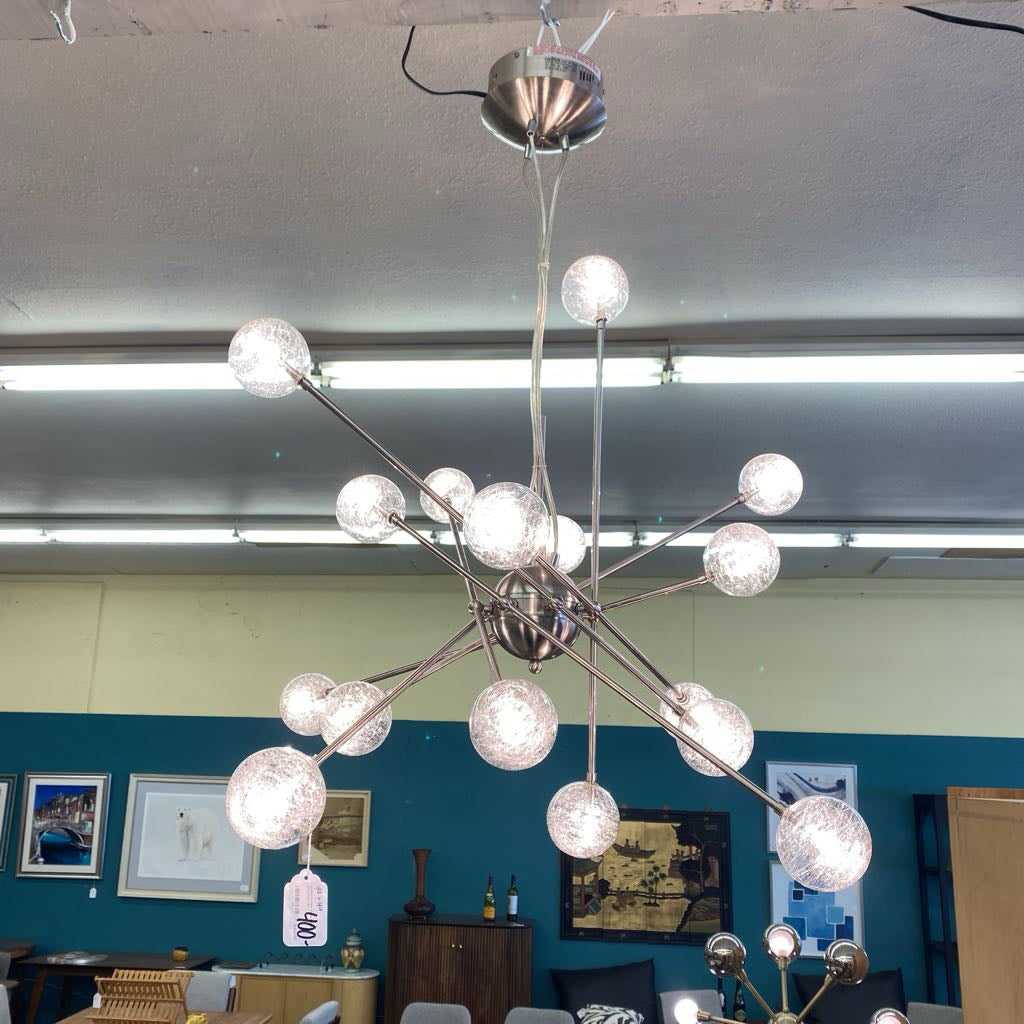 Modern chandelier with multiple spherical lights in a room with blue walls and framed pictures.