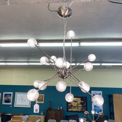 Modern chandelier with multiple spherical lights in a room with blue walls and framed pictures.