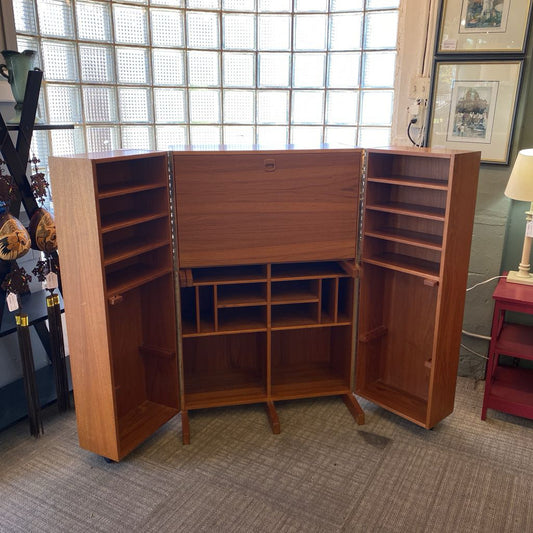 Wooden entertainment center with open doors in a room with a window and lamp.