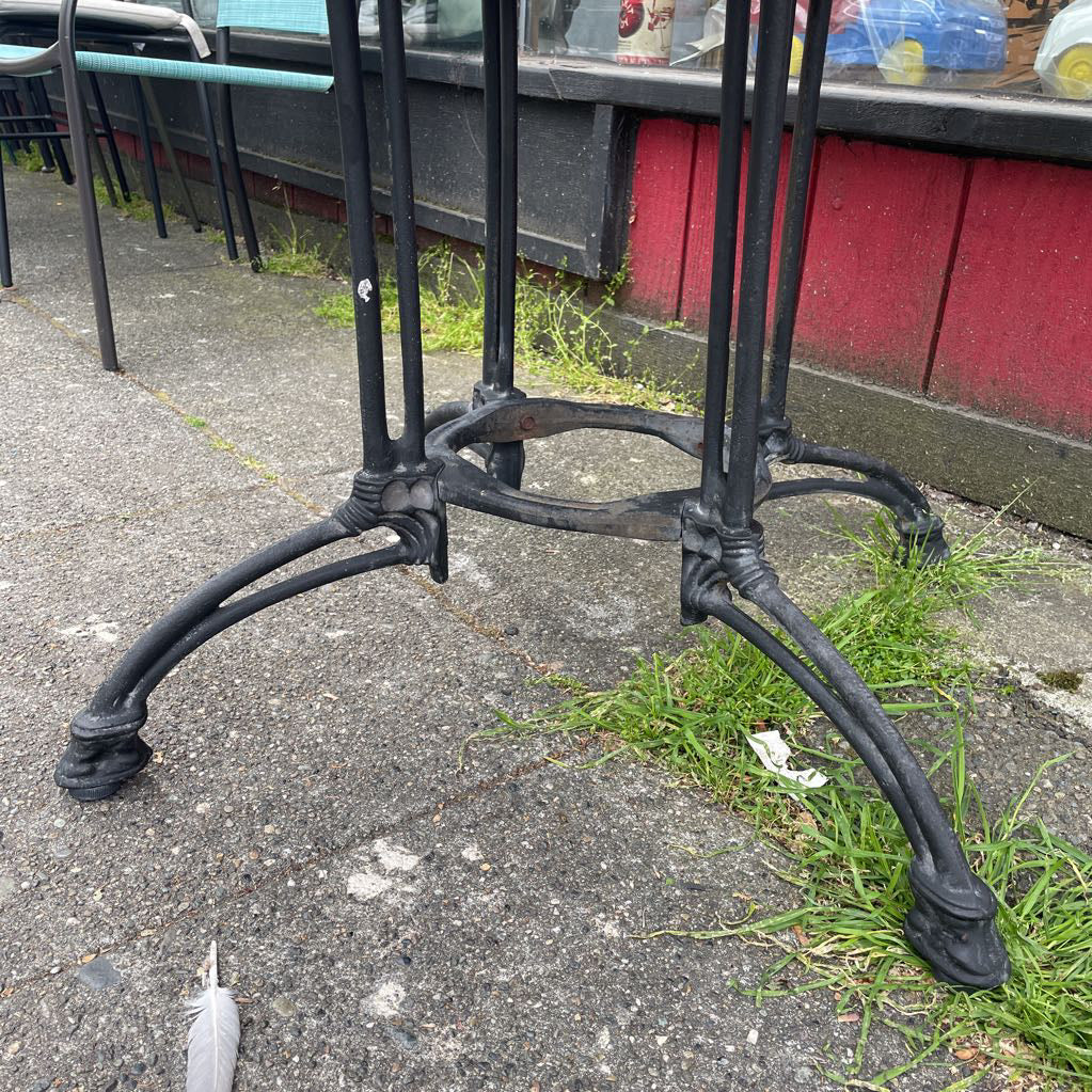 Close-up of the ornate black cast iron base of a bistro table