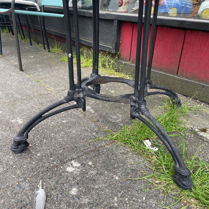 Close-up of the ornate black cast iron base of a bistro table