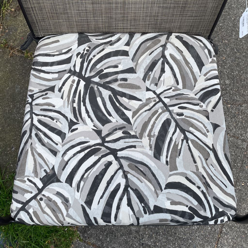 Close-up of the tropical leaf print cushion on an outdoor patio chair